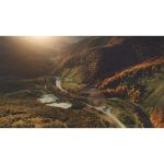 ویدیو استوک پرواز هوایی با پهپاد بر روی دره و رودخانه کوهستانی با مناظر پاییزی خیره‌کننده