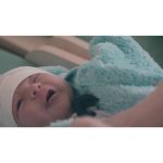 ویدیو استوک مادر جوان مراقب در حال پوشاندن نوزادش