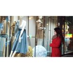 ویدیو استوک زن جوان در کت قرمز در مقابل فروشگاه